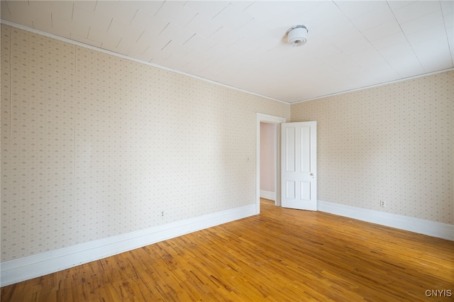 empty room with wood-type flooring and crown molding