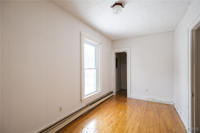 spare room with baseboard heating, plenty of natural light, and light wood-type flooring