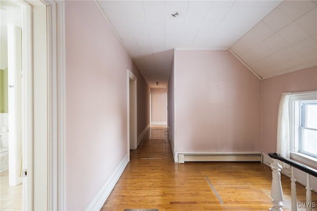 hallway featuring vaulted ceiling, light hardwood / wood-style flooring, and a baseboard heating unit