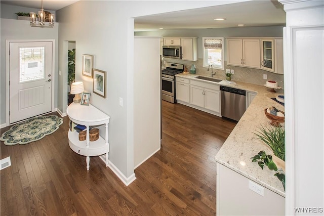 kitchen with pendant lighting, sink, appliances with stainless steel finishes, tasteful backsplash, and light stone counters