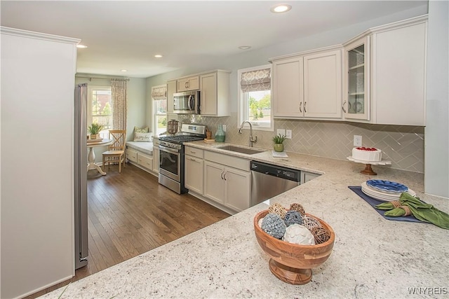 kitchen featuring a wealth of natural light, light stone counters, sink, and appliances with stainless steel finishes