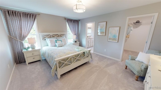 carpeted bedroom with ensuite bath, a spacious closet, and multiple windows