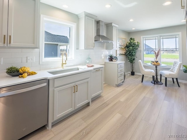 6668 Curtis Ct, Lockport-Town, NY 14094 - kitchen featuring stainless steel dishwasher, wall chimney exhaust hood, a sink, tasteful backsplash, and light wood-style floors