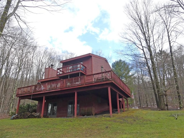 back of property with a wooden deck and a lawn