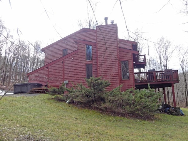 view of side of home with a deck, a hot tub, and a lawn