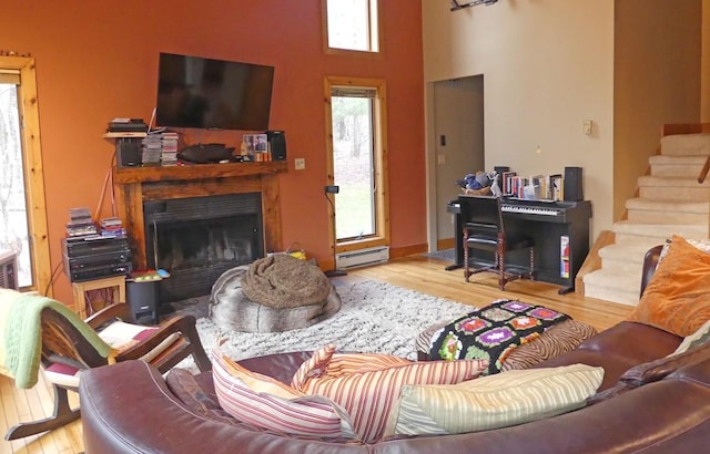 living room with light wood-type flooring, a baseboard heating unit, and a high ceiling