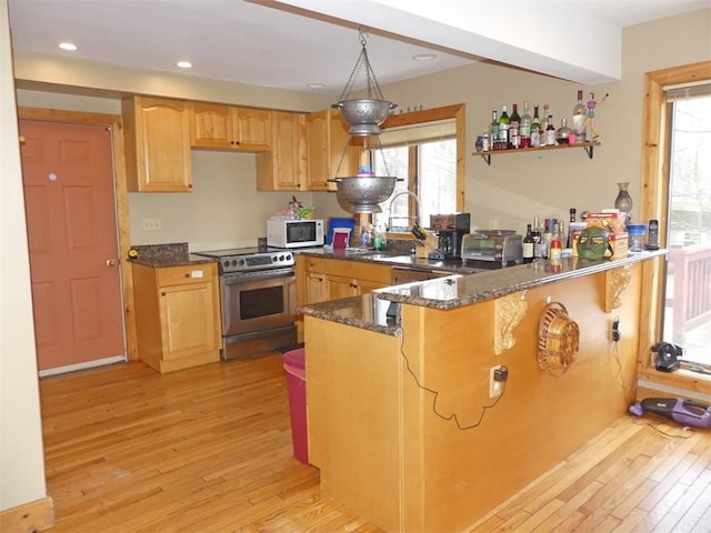 kitchen featuring decorative light fixtures, dark stone countertops, light hardwood / wood-style floors, kitchen peninsula, and stainless steel range with electric stovetop