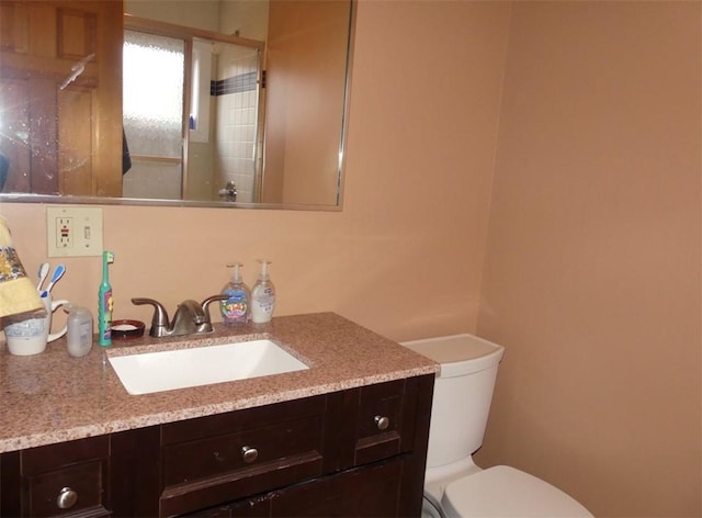 bathroom featuring toilet, an enclosed shower, and vanity