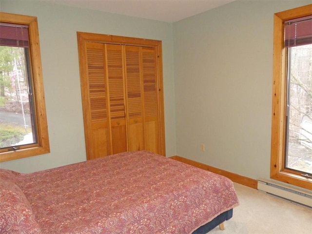 bedroom with a baseboard heating unit, a closet, and carpet