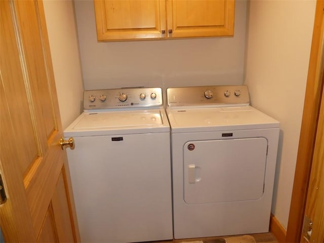 clothes washing area featuring washing machine and clothes dryer and cabinets