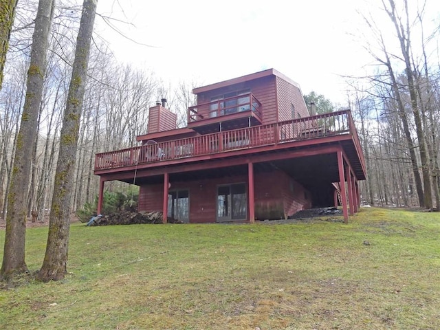 rear view of property with a wooden deck and a lawn