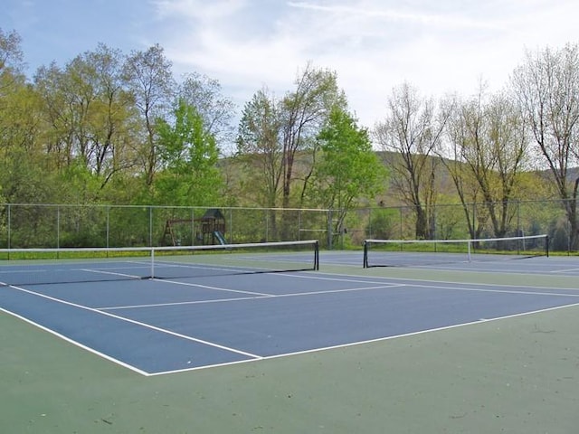 view of tennis court featuring a playground and basketball hoop