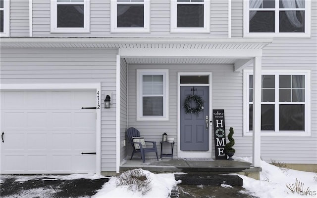 snow covered property entrance with a garage