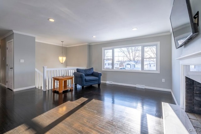 sitting room with a premium fireplace, crown molding, and dark wood-type flooring