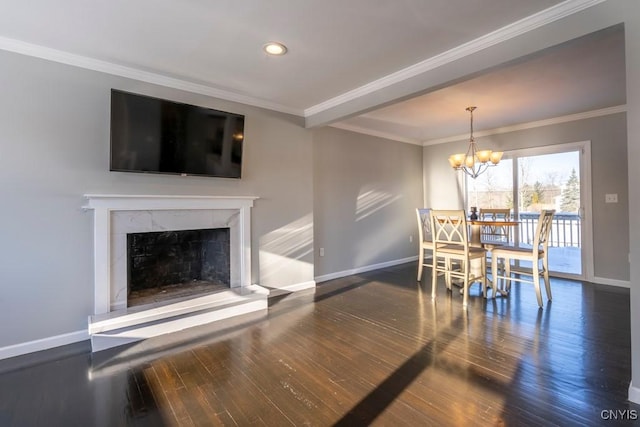 dining room featuring a premium fireplace, crown molding, a chandelier, and dark hardwood / wood-style floors