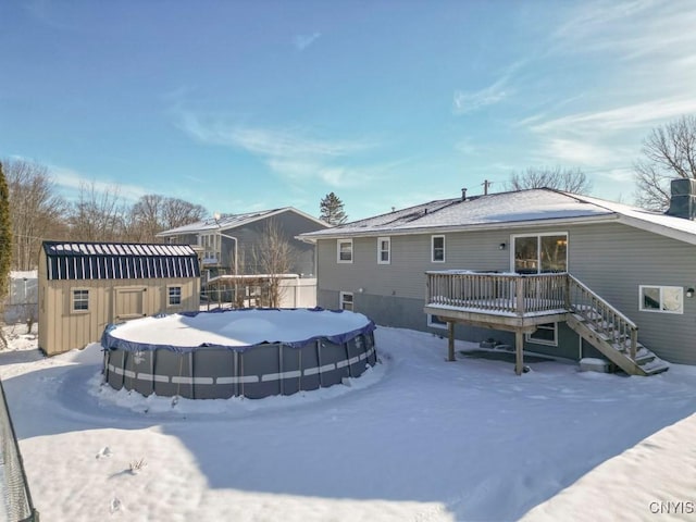 snow covered back of property featuring a shed and a deck