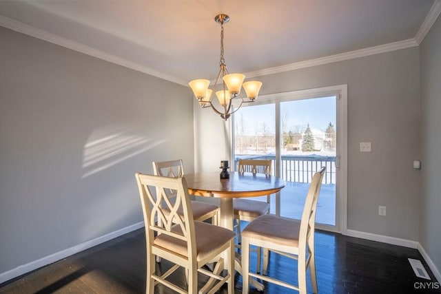 dining space featuring dark hardwood / wood-style flooring, ornamental molding, and a notable chandelier