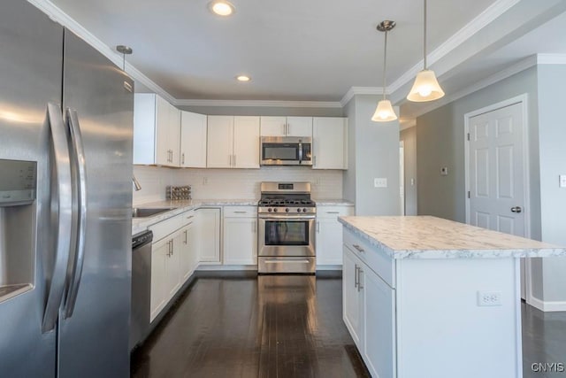 kitchen featuring decorative backsplash, white cabinetry, stainless steel appliances, and hanging light fixtures