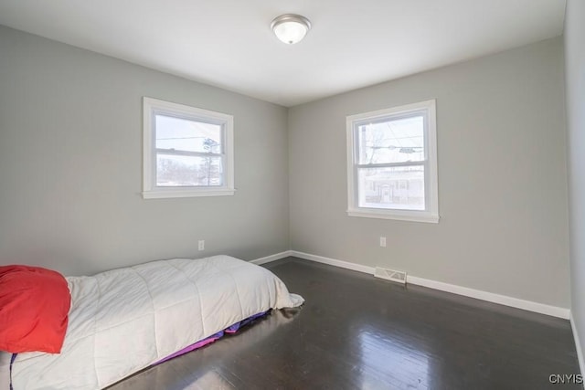 bedroom with multiple windows and dark hardwood / wood-style flooring