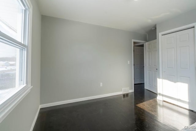 unfurnished bedroom featuring a closet and multiple windows