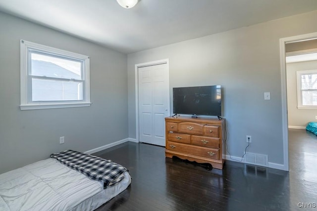 bedroom with dark hardwood / wood-style floors and a closet