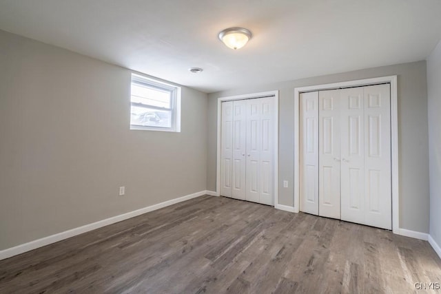 unfurnished bedroom with hardwood / wood-style floors and two closets