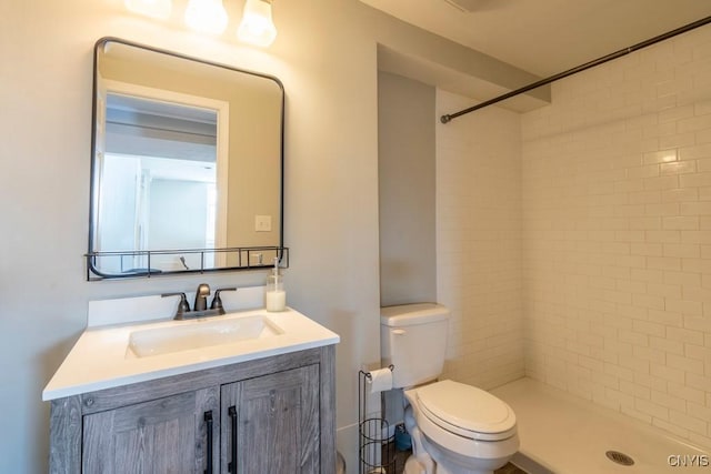 bathroom with vanity, toilet, and tiled shower