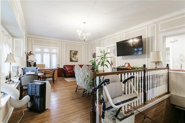 living room with wood-type flooring, ornamental molding, and a chandelier