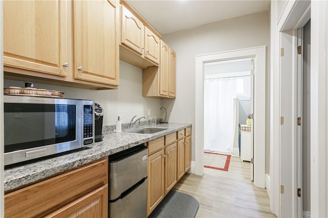 kitchen featuring sink, light stone counters, light brown cabinetry, appliances with stainless steel finishes, and light wood-type flooring