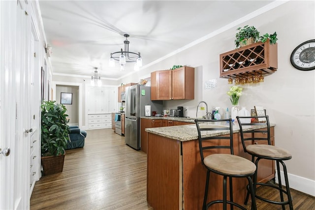 kitchen with hardwood / wood-style flooring, light stone countertops, kitchen peninsula, and crown molding