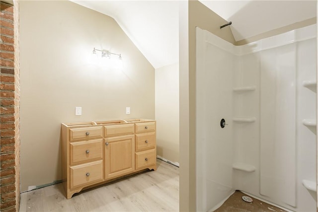 bathroom featuring a shower, vanity, vaulted ceiling, and hardwood / wood-style flooring