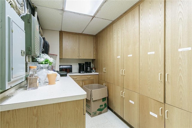 kitchen featuring light brown cabinets and a drop ceiling