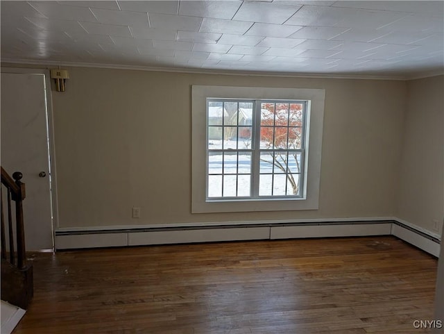 empty room featuring baseboard heating, dark wood-type flooring, and ornamental molding