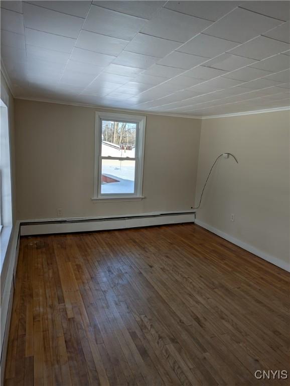 unfurnished room with crown molding, wood-type flooring, and baseboard heating