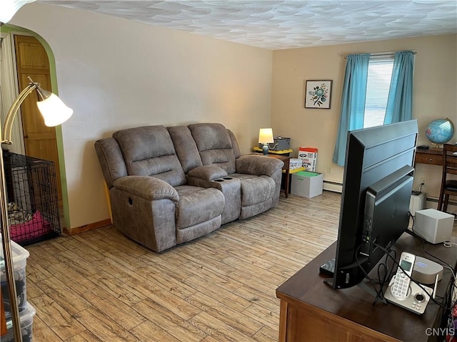 living room featuring a textured ceiling, light wood-type flooring, and a baseboard heating unit