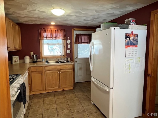 kitchen featuring light tile patterned floors, white refrigerator, range with gas cooktop, and sink