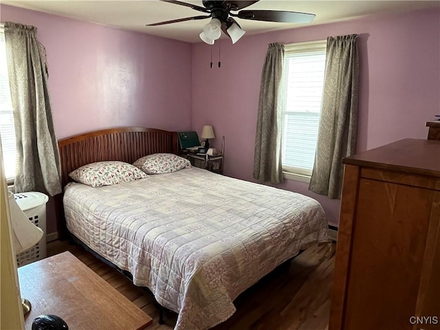 bedroom featuring baseboard heating, ceiling fan, and dark wood-type flooring