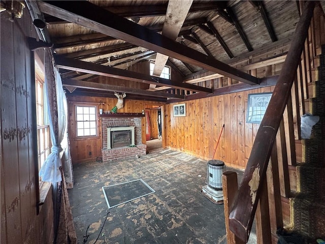 unfurnished living room with a fireplace, wooden ceiling, wood walls, and vaulted ceiling with beams