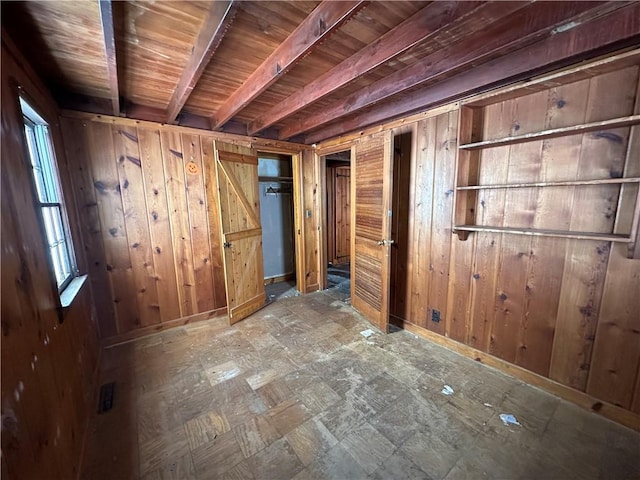 empty room featuring beam ceiling, wood walls, wood ceiling, and a healthy amount of sunlight