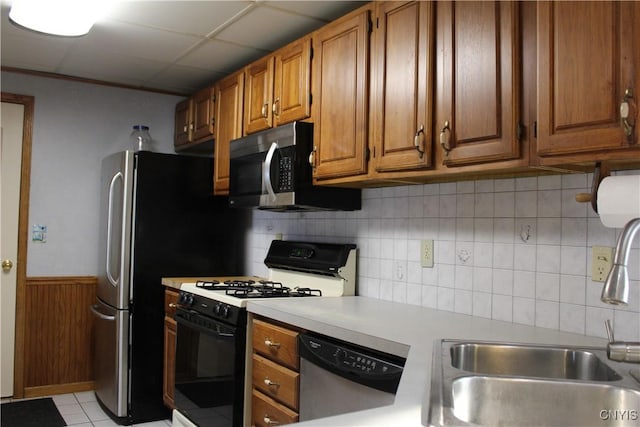 kitchen featuring a drop ceiling, backsplash, sink, light tile patterned floors, and appliances with stainless steel finishes