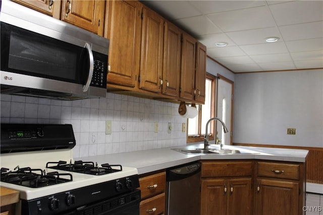 kitchen with a drop ceiling, sink, decorative backsplash, appliances with stainless steel finishes, and kitchen peninsula