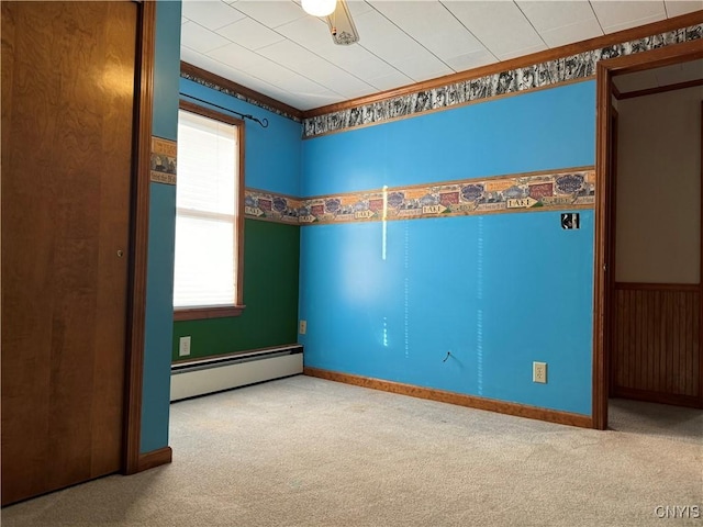 empty room with baseboard heating, ceiling fan, crown molding, and carpet floors