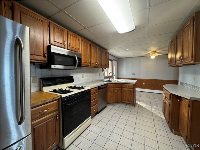 kitchen featuring sink, ceiling fan, light tile patterned floors, kitchen peninsula, and stainless steel appliances