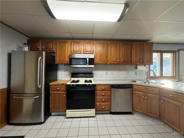 kitchen with a paneled ceiling, decorative backsplash, sink, and appliances with stainless steel finishes