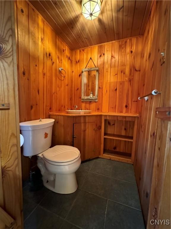 bathroom with wood walls, sink, wood ceiling, and toilet