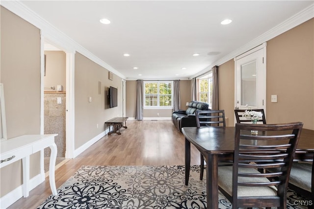 dining space with crown molding and light hardwood / wood-style flooring