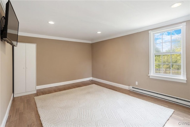 empty room with wood-type flooring, a baseboard radiator, and ornamental molding