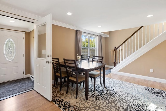 dining room with a baseboard heating unit, ornamental molding, and light hardwood / wood-style flooring