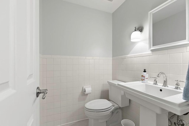 bathroom featuring sink, tile walls, and toilet