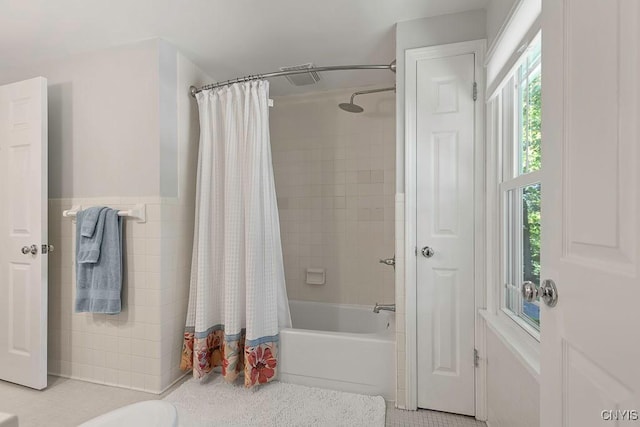 bathroom with shower / bath combination with curtain, a healthy amount of sunlight, tile walls, and tile patterned flooring